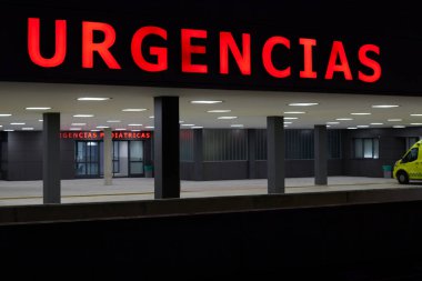 Entrance to a hospital emergency with an ambulance and no people in the lobby. Emergency sign in Spanish