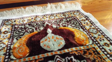 Camide ya da hac ibadetinde Müslümanların kullandığı hacı halısı ya da sejadah. Ahşap arka planda. Hafif ve yakın çekim.