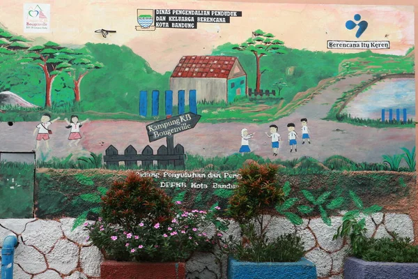 A painting on the wall about family planning counseling in the city of Bandung with decorative plants and flowers in front of it.