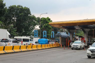 Bandung, Endonezya - 13 Nisan 2023: Arabalar arka planda mavi gökyüzü ile Buah Batu geçiş kapısından geçer.