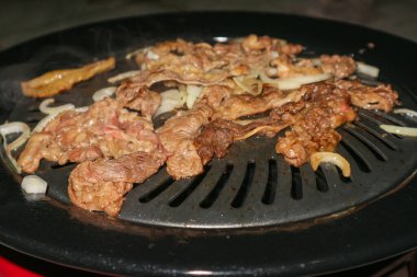 Izgara yapılan et dilimleri ve soğanlar.