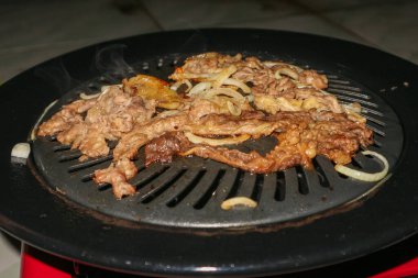 Izgara yapılan et dilimleri ve soğanlar.