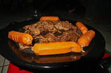 Izgarada sığır eti, soğan ve sosis var.