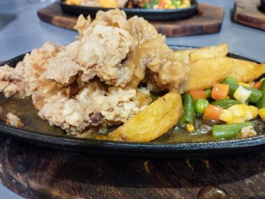 Biftek fileto bifteği una bulanmış ve elektrikli ocakta kızartılıyor. Patates, bezelye, havuç ve sosla birlikte. Waroeng Biftek Bandung 'un orijinal mutfağı. Popüler et lokantalarından biri..