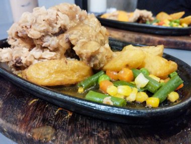 Biftek fileto bifteği una bulanmış ve elektrikli ocakta kızartılıyor. Patates, bezelye, havuç ve sosla birlikte. Waroeng Biftek Bandung 'un orijinal mutfağı. Popüler et lokantalarından biri..