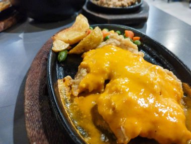 Biftek fileto bifteği una bulanmış ve elektrikli ocakta kızartılıyor. Patates, bezelye, havuç ve sosla birlikte. Waroeng Biftek Bandung 'un orijinal mutfağı. Popüler et lokantalarından biri..