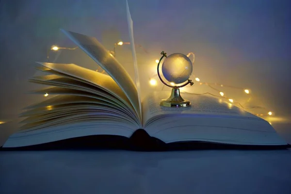 open book with a glowing lights glass globe