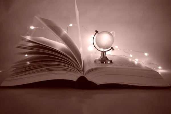 Arkaplanda cam küre açık kitap sitesi sepya ışıkları
