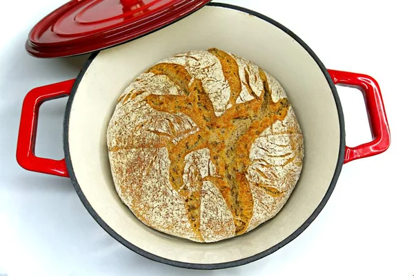 baked sour dough bread home made in a red cast iron pot isolated