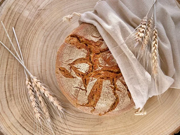 fresh homemade bread on a wooden background in linen bag wheat grains