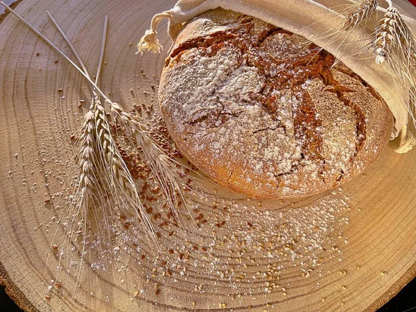 fresh homemade bread on a wooden background in linen bag wheat grains
