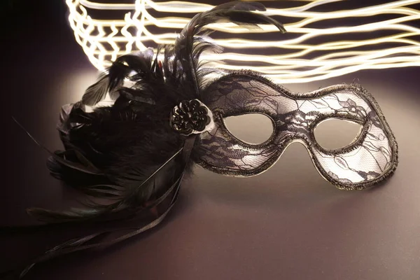 Siyah arka planda Venedik karnaval maskesi, arkasında ışık