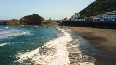 Hava manzaralı siyah volkanik kum plajı. Anaga sıradağları, Tenerife 'nin yeşil kuzey kıyıları, Kanarya Adaları, İspanya, Avrupa. Kardiyo çalışması. Sabah koşusu. Mavi okyanus dalgaları köpürüyor.