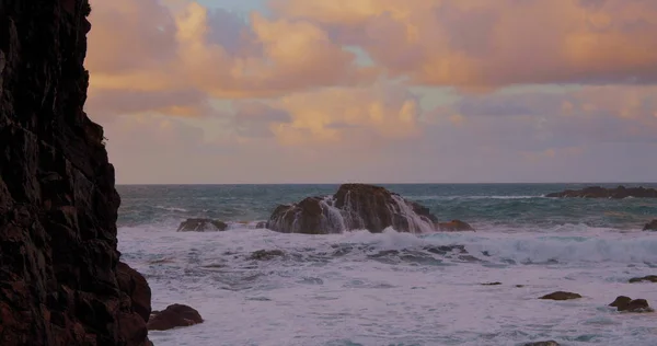 Atlantik Okyanusu üzerinde yükselen kayalar. Gün batımında dalgalar kaya parçalarına çarpıyor. Yavaş çekim alacakaranlık havası. Tenerife, Kanaryalar. İspanya