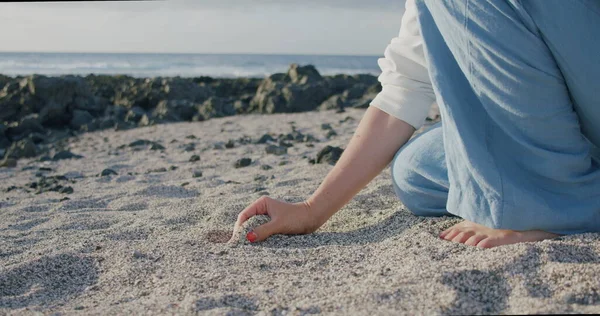 Genç bir kadın tropik plajda beyaz kum tutuyor. Tenerife.