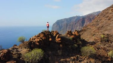 Volkanik ada, soğutulmuş lav dev dağlar oluşturdu. The Giants, Los Gigantes. Erkek turist uçurumun zirvesine ulaştı. Kanarya Adası Tenerife. Kaya oluşumları 500-800 metre yükseklikte yükseliyor. Havadan