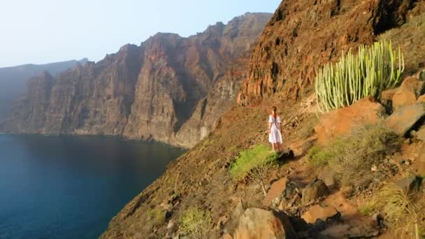 山の上に立つ白いドレスの女性は 海の風景をお楽しみください 風が彼女のドレスを吹いた 自然概念 パラダイス島テネリフェ島 スペイン ヨーロッパ 晴れた夏の日 青い海 — ストック動画