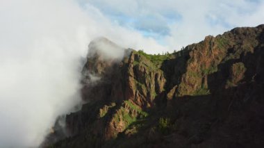 Teide Ulusal Parkı 'ndaki fırtınalı ve güneşli havada dağın tepelerinde sis var. Bulutlar dağın tepesinde yuvarlanıyor. Doğa geçmişi. Tenerife Kanarya Adaları İspanya Avrupa.