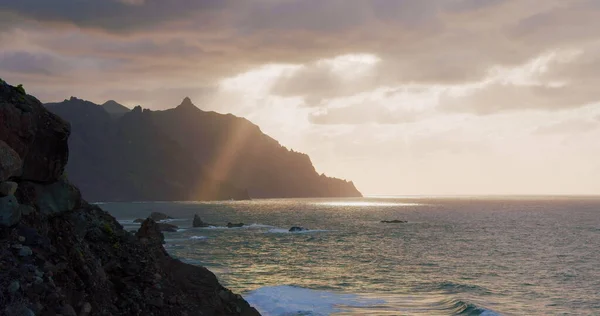 Gün batımında kumlu plajlı güzel doğal manzara ve büyük taşlar. Okyanus dalgaları kıyıya vuruyor. Tenerife 'de popüler bir turizm merkezi. Seyahat.