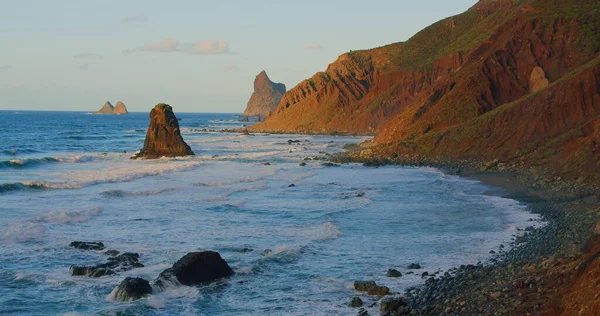 Large waves with foam roll on hilly ocean rocky beach at sunset. Relax 4k enjoy the landscape view. Tenerife, Canary Islands, Spain.
