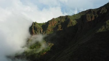 Yeşil dağların tepesindeki bulutlarda doğal güneş ışığıyla uçuyor. Kozalaklı ormanlı yüksek tepeler, harika bir sabah güneşi. İnanılmaz bir manzara. Doğa geçmişi. Volkanik Natioanan 'ı takip edin!
