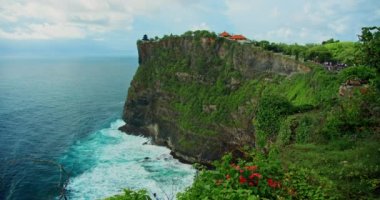 Uluwatu Tapınağı Pura Luhur Hindu 'nun bulunduğu el değmemiş tropik yeşil sahil uçurum ve Bali adasında sonsuz okyanus ufku. Yaz tatili. Bali deniz suyu ve kayalık kıyı şeridi. Parazit