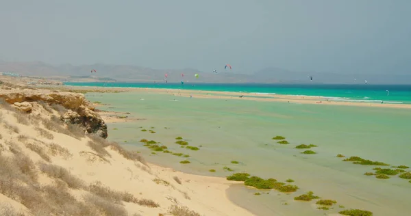 Mavi gökyüzünün önündeki vahşi beyaz kumsalda paraşütler. Cennet Adası 'nda yamaç paraşütü deneyimi yaşayan turistler. Tanımlanamayan insanlar uçuyor, yamaç paraşütü yapıyor..