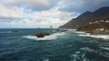 Gün batımında mavi Atlantik Okyanusu suyuyla kayalık sahil şeridinde uçurumlar üzerinde uçmak. Gökyüzündeki bulutlar. Sinematik dron görüntüleri. Tenerife Kanarya Adaları İspanya Avrupa.