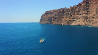 Los Gigantes 'in yüksek volkanik dağları ile Atlantik Okyanusu' nun derin sularında uçan hava uçuşu. Sakin denizde turistik tekne ve yatlar yüzüyor. Yalan aktivitesi. Güzel güneşli bir gün