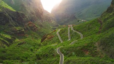 Renkli günün güzel hava manzarası Masca Vadisi 'ndeki yeşil manzara ve güneş doğarken vadideki küçük dağ köyü. Kaya tepelerinin büyülü parıltısı. Tenerife Kanarya Adaları İspanya Avrupa.