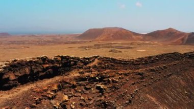 Fuerteventura, Kanarya Adaları, İspanya. Volkanik arazide yürüyüş yapan genç bir kadın, Calderon Hondo volkanının dev bir kraterinde lav kayaları. Seyahat mesafesi. Terk edilmiş Mars 'ın havadan görünüşü