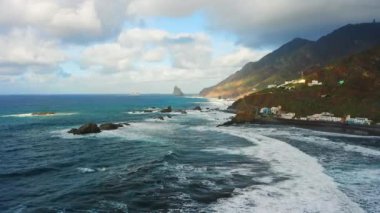Gün batımında mavi Atlantik Okyanusu suyuyla kayalık sahil şeridinde uçurumlar üzerinde uçmak. Gökyüzündeki bulutlar. Sinematik dron görüntüleri. Tenerife Kanarya Adaları İspanya Avrupa.