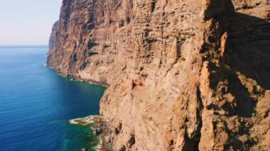 Hava, okyanustaki kayalık boş uçurumun görüntülerini yukarı kaldırıyor. Atlantik kıyısı. Güzel doğa Tenerife Adası. Seyahat yaz tatili konsepti. Büyük kayalar çorak dağlar. Los Gigantes. Derin gök mavisi