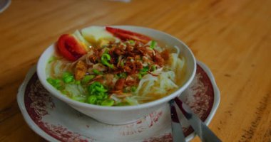 Bir kase soto ayam çorbası tavuk, erişte, sebze, yumurta, yeşillik. Lezzetli yemekler, Endonezya geleneksel yemekleri. Seçici odaklanma. Yakın çekim, yavaş çekim.