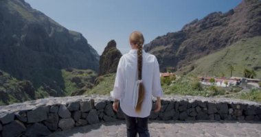 Genç kadın, İspanya 'nın Kanarya Adaları' ndaki Tenerife adasındaki Masca Vadisi ve köyü manzarasının tadını çıkarıyor..