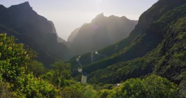 Masca Vadisi ve Gorge 'da güzel bir günbatımı, Tenerife, Kanarya Adaları, İspanya. Güneş ışığı dağ sıralarının arasından doğuyor. Harika bir manzara. Elle tutulan yüksek kalite atış. Ağır çekim. Hareket eden yol