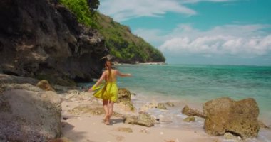 Güneşli bir günde kumlu tropikal yeşil bovling plajında yürüyen yalnız ve güzel bir kadının silueti. Endonezya 'daki Cennet Bali Adası. El bilgisayarı görüntüleri.