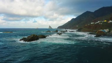 Gün batımında mavi Atlantik Okyanusu suyuyla kayalık sahil şeridinde uçurumlar üzerinde uçmak. Gökyüzündeki bulutlar. Sinematik dron görüntüleri. Tenerife Kanarya Adaları İspanya Avrupa.