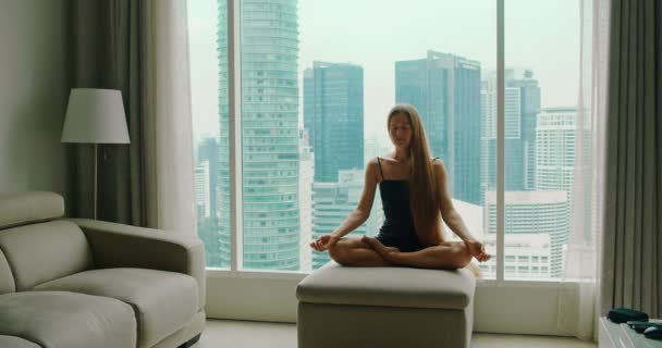 Dziewczyna Siedzi Medytując Kanapie Przy Oknie Widokiem Drapacze Chmur Dużego — Wideo stockowe