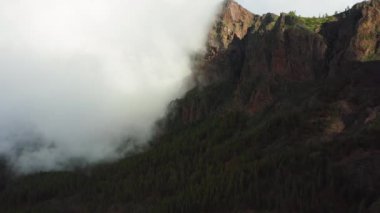 Teide Ulusal Parkı 'ndaki fırtınalı ve güneşli havada dağın tepelerinde sis var. Bulutlar dağın tepesinde yuvarlanıyor. Doğa geçmişi. Tenerife Kanarya Adaları İspanya Avrupa.