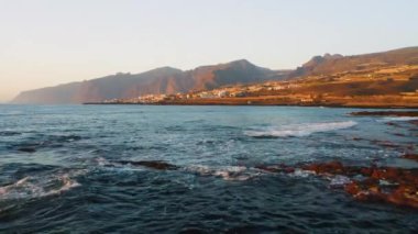 Havadan. Volkanik kayalık plajı. Okyanus sakin dalgalar, şeffaf su. Dünyayı keşfetmek. Tenerife. Kanarya adaları, İspanya. Güzel bir şehir tatil köyü. Seyahat bağımlısı. Gün batımı. Kimse.