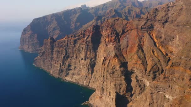 空中飞越峭壁 深蓝色的大海 巨大的悬崖峭壁 西班牙 特内里费 白色的薄雾宁静的 几艘帆船荒芜的岩石火山 — 图库视频影像