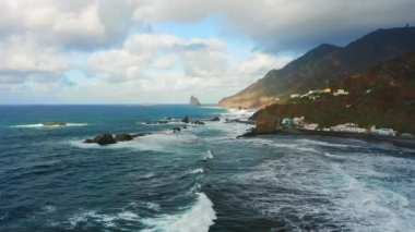 Ocean rocky coastline volcanic seaside of Benijo Beach on Tenerife Island. Natural landscape, clouds on blue sky. Aerial flight over foamy waves crash on wild shore. Scenery sea. Tourist attraction