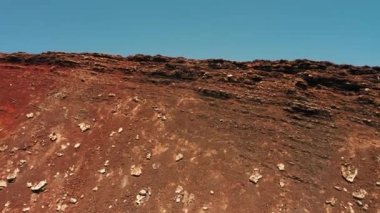 Epic drone flight inside crater named Calderon Hondo volcano. Rise from the bottom of crater straight up into blue sky. Fuerteventura Island. Spain. Traveler enjoys lava desert brown-red landscape