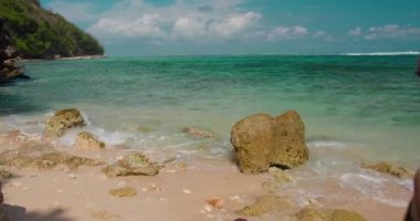 Turist kadın Endonezya 'nın Bali Adası' ndaki kumlu yeşil bovling plajının tadını çıkarıyor. Sahilde tek başına yürüyen kızın dikiz görüntüsü. Okyanus kıyısında. Deniz dalgaları köpüğe çarpar. Rahat ol. Yakın plan..