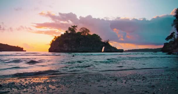 在色彩艳丽的落日下 海浪在海滩上蔓延开来 海洋水晶湾 太阳光在水面上的反射 山的轮廓 慢动作没人 — 图库视频影像