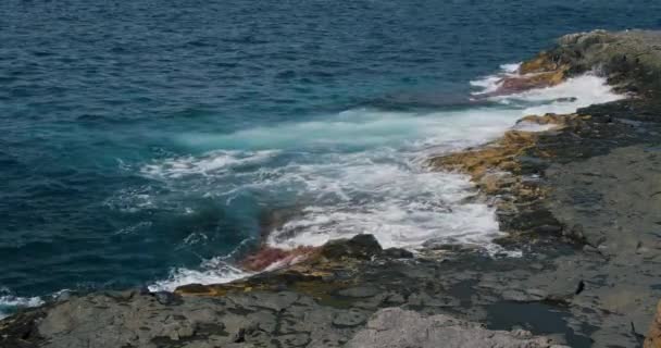 海浪冲刷着黑色的火山岩 浪花飘扬在海岸上 水面上的光反射 高质量的4K镜头 — 图库视频影像