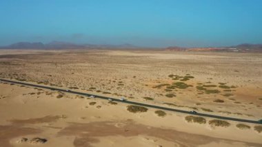 Corralejo, Fuerteventura, Kanarya Adaları, İspanya 'daki kum tepeleri boyunca asfalt yol. Atlantik Okyanusu boyunca otoban manzarası. Doğal Park. Seyahat sıkıntısı. Her yere gidin. Kimse..