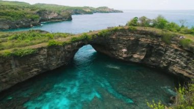 Travel destination on Bali. Scenery natural pool in shape of a circle with a picturesque stone bridge over the ocean. Broken Beach in Nusa Penida, Indonesia. Aerial view.