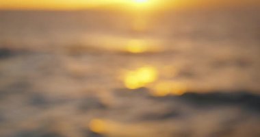 Blurred natural background of sea waves at sunset. Sun glare on ocean surface.